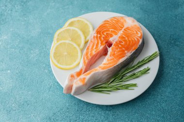 Limon dilimli çiğ somon bifteği ve beyaz tabakta biberiye.