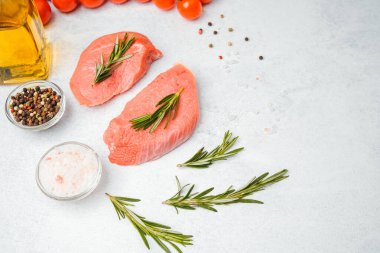 Beyaz arka planda baharatlı dana bifteği ve bitkilerin üst görüntüsü, yakın plan yağ ve biber dahil.