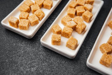 Esmer şeker küpleri beyaz tepsilere yerleştirilmiş sıradan bir olay sırasında servis edilmeyi bekliyor..