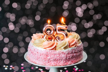 Mumlu pembe bir pasta neşeli bir 85 'inci yaş günü kutlaması gösteriyor..