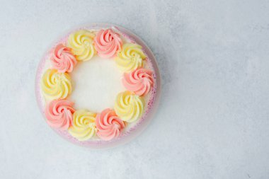 Açık bir yüzeyde pembe ve sarı girdaplarla süslenmiş pasta..