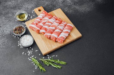 Pastırmaya sarılı çiğ et ruloları ahşap tahtaya baharatlı.