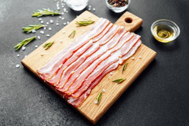 Siyah yüzeyde baharat ve biberiye ile sıralanmış jambon dilimleri.