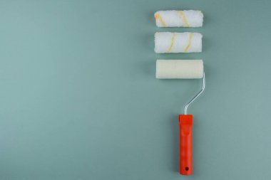 Boyama çeşitliliği ve DIY konsepti için yeşil arka planda üç boya silindiri