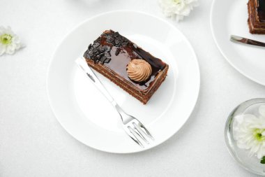 Krema soslu çikolatalı pasta dilimi ve beyaz tabakta zengin jöle, çatal