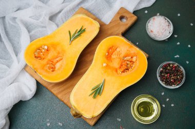 Tahta bir tahtanın üzerinde baharatlı ve yağlı biberiye filizi ile yarıya indirilmiş taze tereyağı ezmesi..