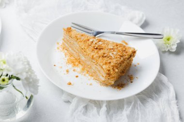 Katmanlı millefeille keki beyaz tabakta çatallı, kremalı tatlı, narin hamur işi