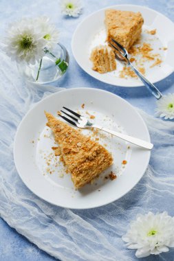 Napolyon keki tatlı katmanları puf böreği ve krema tabaklara çatal ve beyaz çiçeklerle doluyor