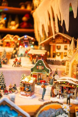 Minyatür kış köyü sahnesi. Parlayan ışıklar ve buz saçakları.
