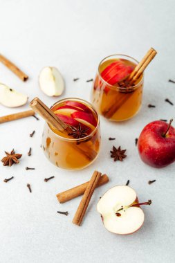 Tarçın çubuklu iki bardak baharatlı elma şarabı, yıldız anason, karanfil ve elma dilimleri..