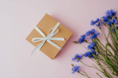 Pembe arka planda hediye kutusu ve çiçek.