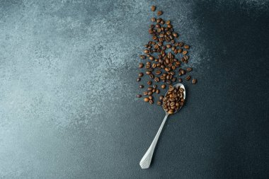 Koyu arkaplanda metal kaşıkta kahve çekirdekleri