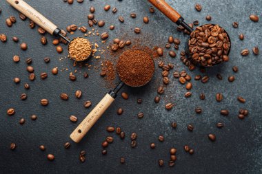Ground Coffee ve gri arka planda kepçeli fasulyeler.