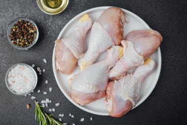 Tavuk budu çiğ, baharatlı ve otlu beyaz tabakta.