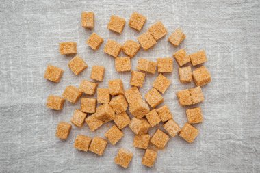 Küçük kahverengi şeker küpleri desenli keten kumaşa saçılmış..