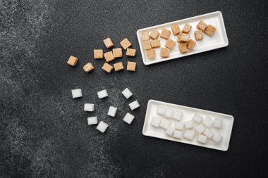 Karşılaştırmak için parlak tepsilerde düzgün sıralanmış kahverengi ve beyaz şeker küpleri..