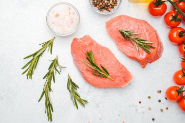 Beyaz arka planda baharatlı dana bifteği ve bitkilerin üst görüntüsü, yakın plan yağ ve biber dahil.