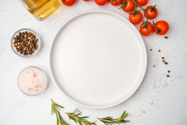 Domates, biberiye, tuz, yağ ve biber içeren yemek malzemelerinin bulunduğu boş beyaz tabağın üst görüntüsü