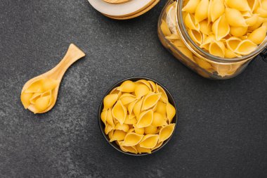 Pişmemiş makarna kabuğu şekilleri mutfak tezgahında bir kase ve kavanozda dizilmiş..