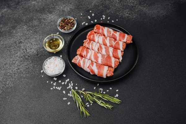 Domuz pastırmasına sarılı çiğ et ruloları ve baharatlar.