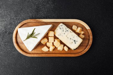 Çeşitli peynirler tahta bir tahtada, küp ve kama ile sıralanır..
