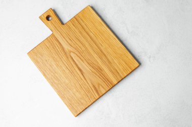 Tahta kesme tahtası hafif bir yüzey üzerinde yemek hazırlığı için duruyor..