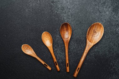 Koyu bir taş yüzeyine yerleştirilmiş dört farklı boyutta tahta kaşık..