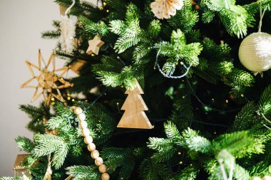 Ahşap süslemeler ve sıcak ışıklarla süslenmiş yeşil çam ağacı, bayram kutlaması