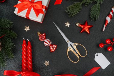 Noel hazırlıkları: hediyeler, makas, mumlar, köknar dalları, koyu arkaplan süsleri