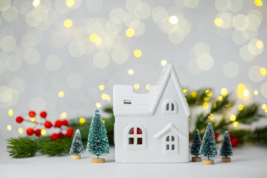 Beyaz seramik ev ve kırmızı böğürtlenlerle çevrili küçük çam ağaçları..