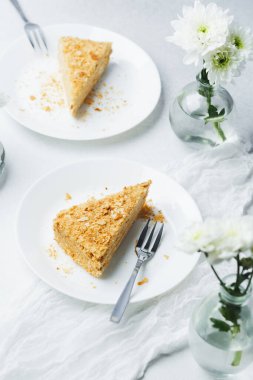 Beyaz tabakta kremalı ve puf börekli Napolyon keki dilimi, lezzetli bir tatlı.