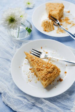 Napolyon pastası kremalı dilimler ve beyaz tabaklarda servis edilen puf börekleri.