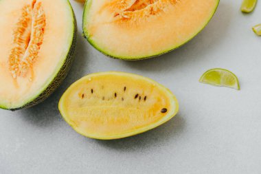 Kavun ve sarı karpuz, açık gri bir yüzey üzerinde limon dilimli..