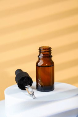 Bej üzerine kehribar camlı kozmetik serum damlası şişesi.