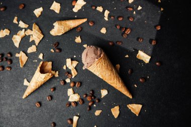 Kahveli dondurma külahı ve siyah arka planda waffle kırıntıları.