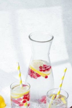 Limon dilimleri ve sarı çizgili kamışlarla servis edilen kırmızı meyveli içecek.