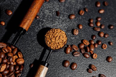 Koyu arkaplanda kahve çekirdekleri ve kepçeli kahve taneleri.