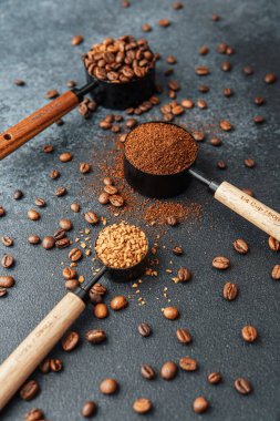 Ground Coffee ve gri arka planda kepçeli fasulyeler.