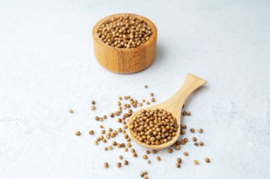 Beyaz arka planda kişniş tohumlu ahşap kase ve kaşık