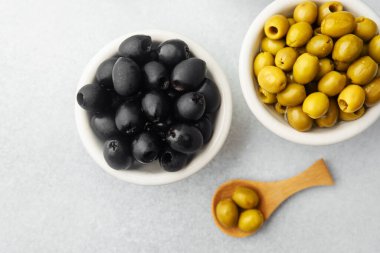 Gri arkaplandaki zeytinler, yeşil zeytinler, siyah ve kalamata zeytinleri.