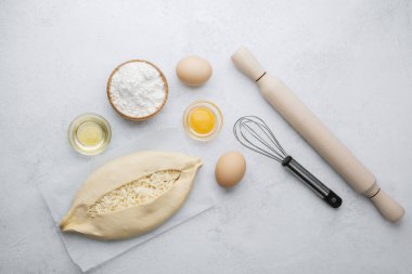 Parşömen üzerinde peynir ve fırın malzemeleri olan fırınlanmamış khachapuri.