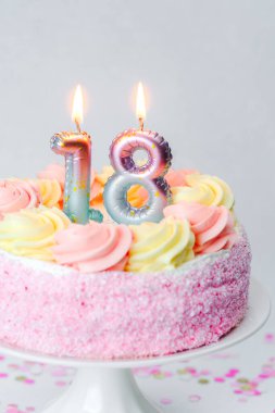 Yumuşak kremalı renkli bir pasta ve mumlar 18. yaş günü kutlaması için..