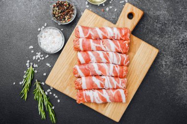 Pastırmaya sarılı çiğ et ruloları ahşap tahtaya baharatlı.