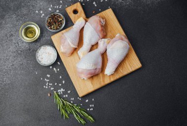 Ahşap tahtada çiğ tavuk budu ve baharat.