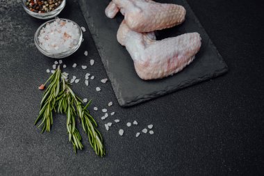 Siyah tahtada çiğ tavuk kanadı ve baharat.