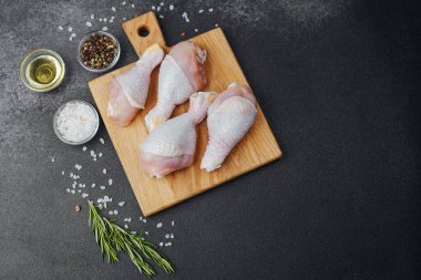 Ahşap tahtada çiğ tavuk budu ve baharat.