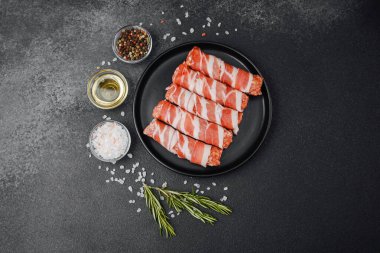 Domuz pastırmasına sarılı çiğ et ruloları ve baharatlar.