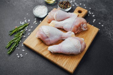 Ahşap tahtada çiğ tavuk budu ve baharat.