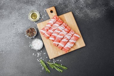 Pastırmaya sarılı çiğ et ruloları ahşap tahtaya baharatlı.