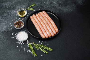 Siyah tabakta çiğ domuz sosisi ve biberiye.